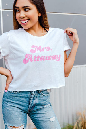 A woman wears a white t shirt which say "Mrs. Attaway" in pink