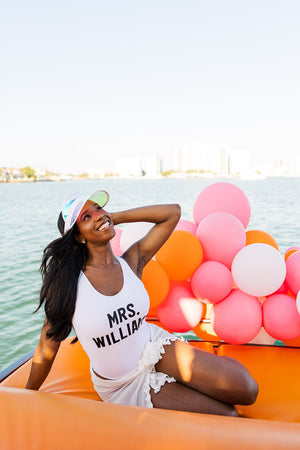 A bride-to-be lays on a boat wearing a personalized swimsuit that reads "Mrs. Williams"