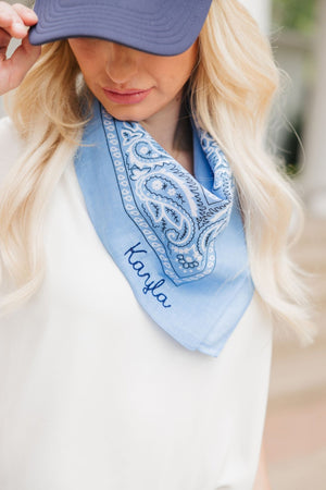 A blonde wears a blue bandana embroidered with her name "Kayla"