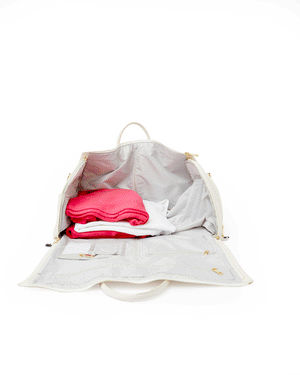 A white duffel is packed up and closed to reveal an embroidered monogram on the front.