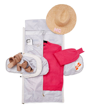 A garment bag is laid open with various clothes and travel accessories inside.