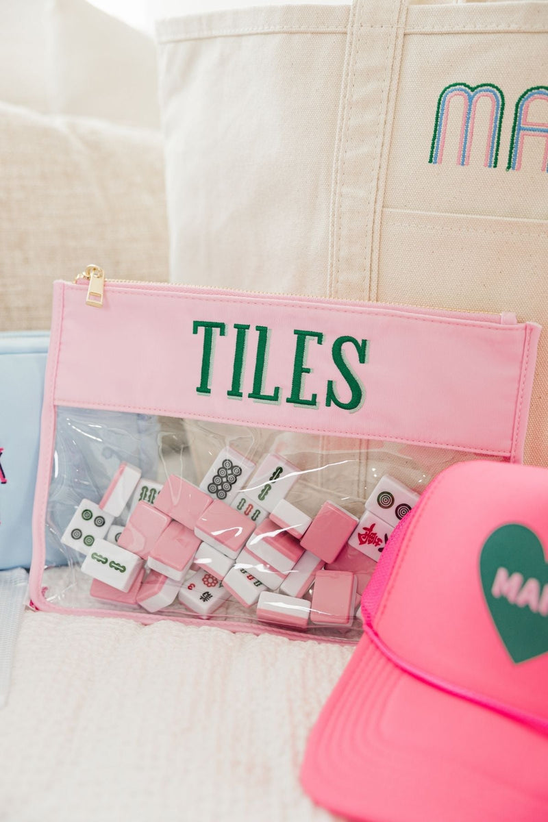 Mahjong tiles are stored in a pink, clear pouch that reads "Tiles"