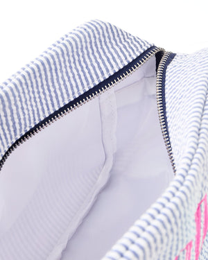 A seersucker pouch is unzipped to show the lining of the interior.