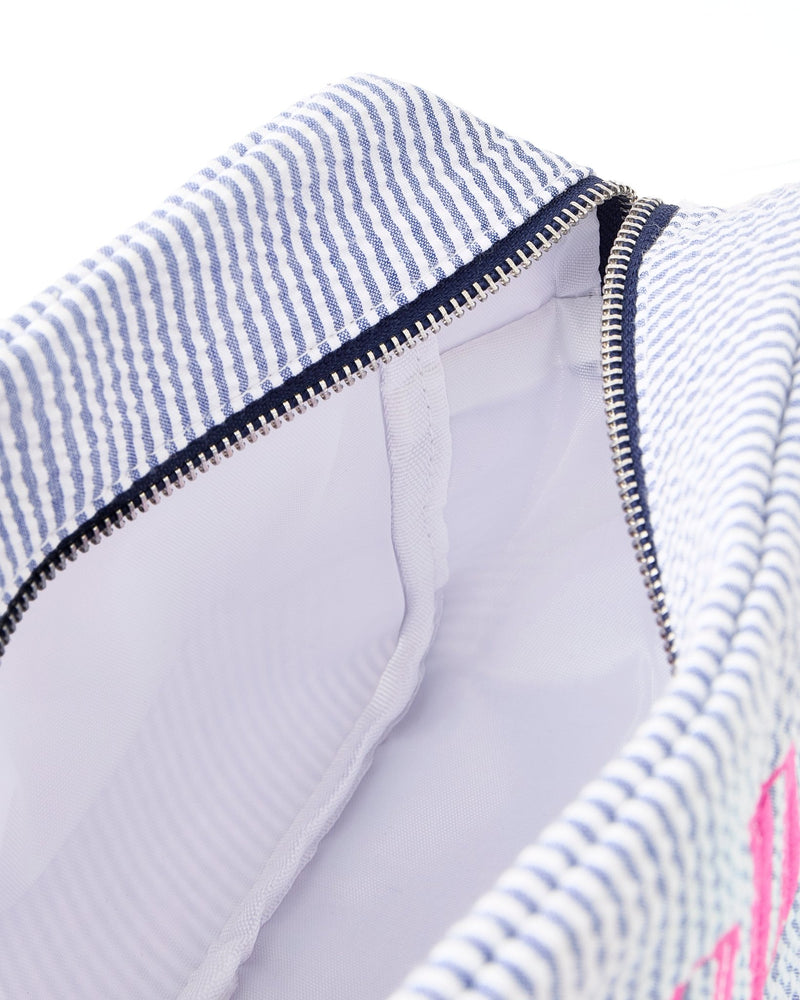 A seersucker pouch is unzipped to show the lining of the interior.