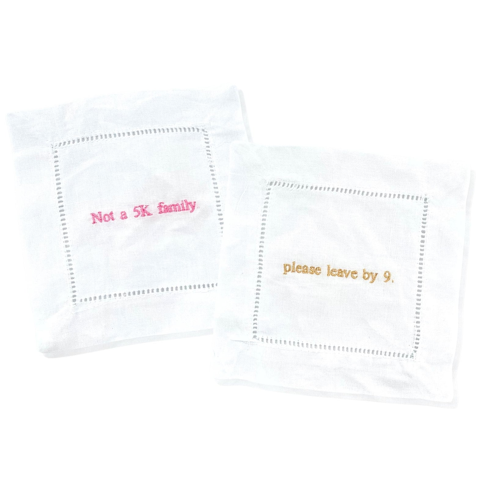 Two cocktail napkins customized with ironic phrases in pink and gold thread