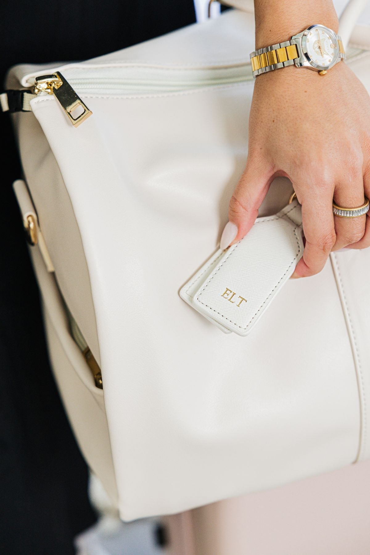 A white, black, and tan leather hat clip are personalized with gold metallic monograms.