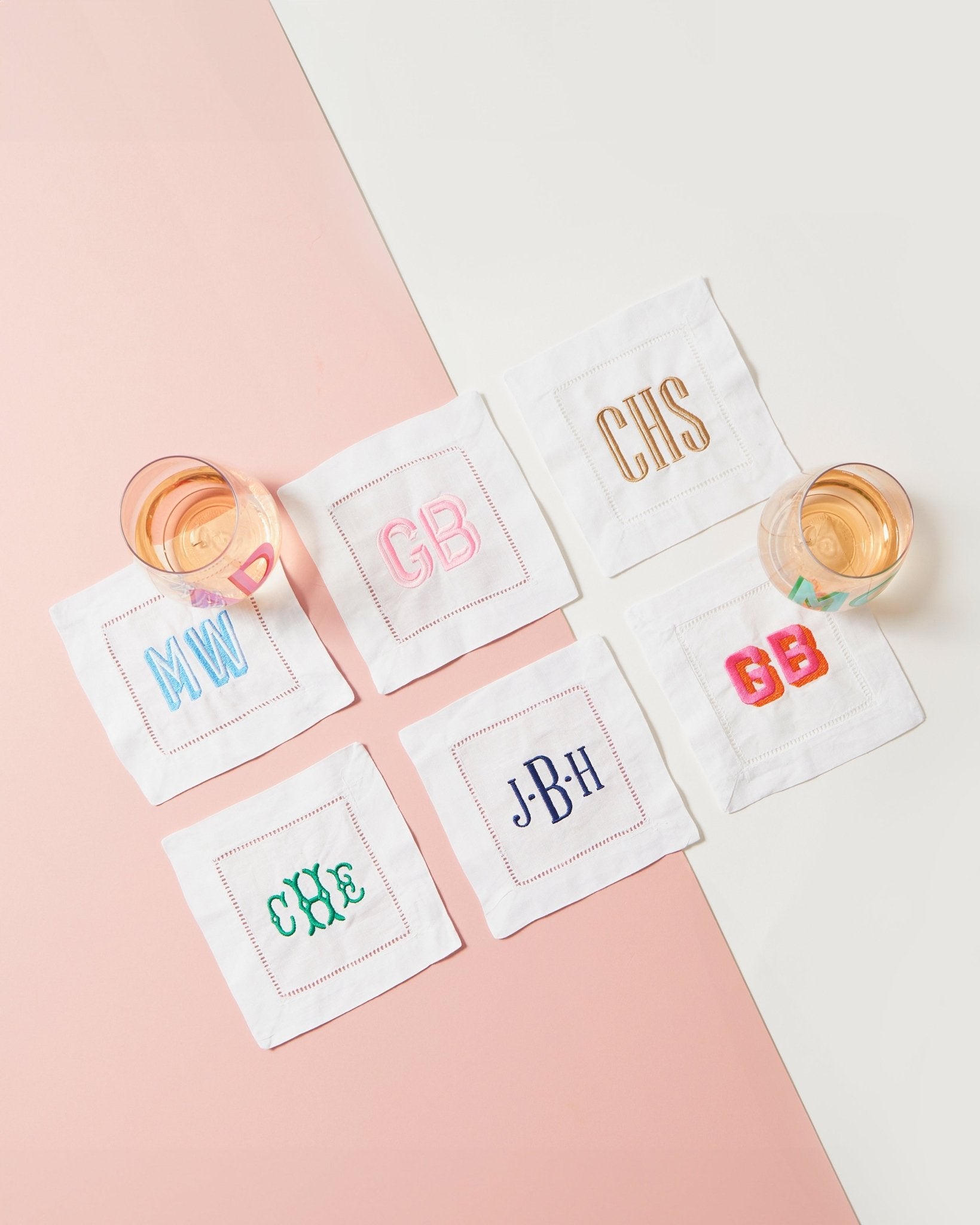 Two monogrammed cocktail napkins are laid out on a white background to show off some of the customization options.