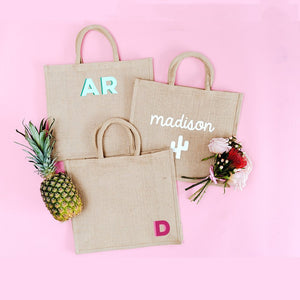 Three jute totes are personalized with different mongram and name options.
