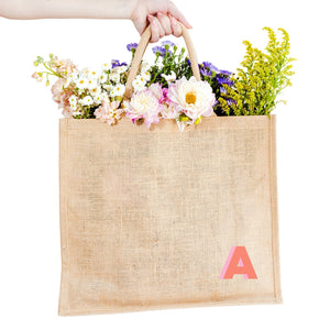 A jute tote with an "A" monogrammed on the bottom corner