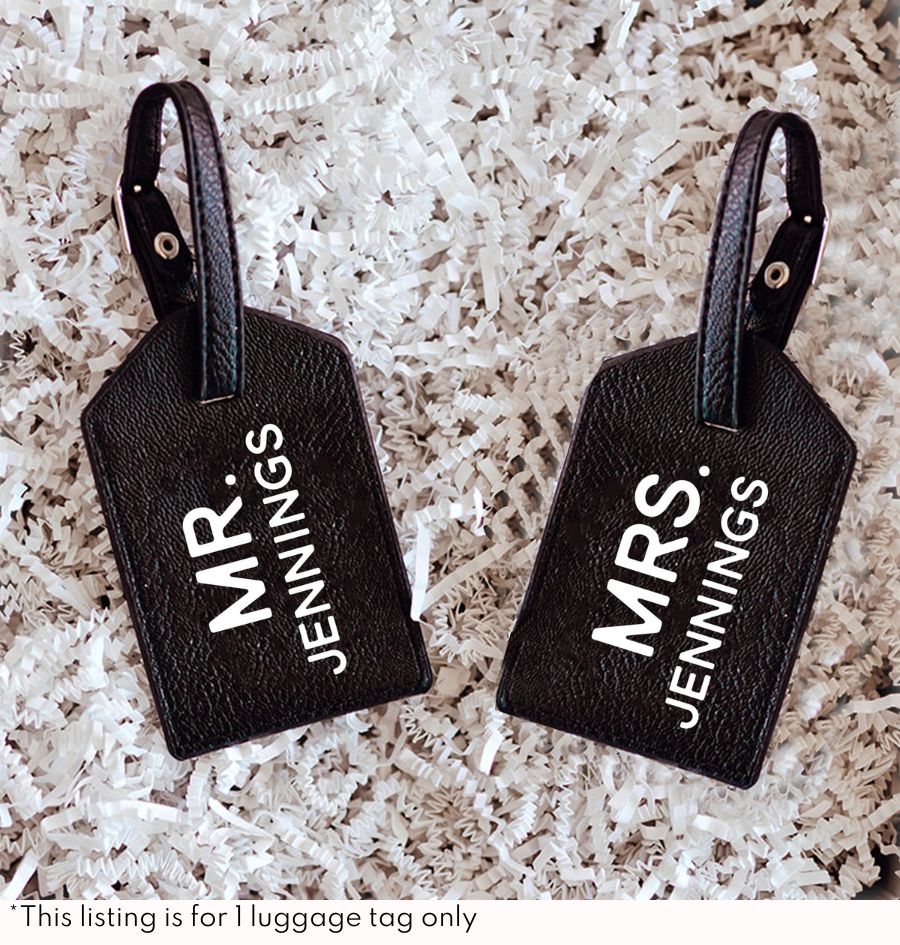 Two white luggage tags with gold lettering customized for a Mr. & Mrs.