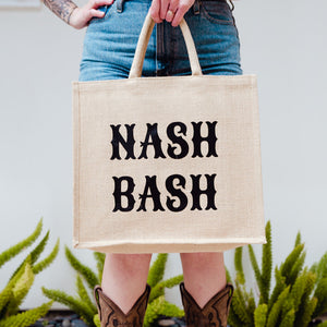 A person holds a tote bag which reads "Nash Bash" in big, black font.