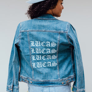 A woman wears a jean jacket with a name on the back.