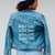 A denim jacket is customized with a repeating last name printed on the back.