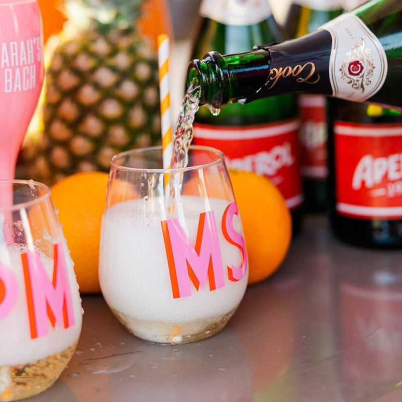 A monogrammed wine glass is filled with wine