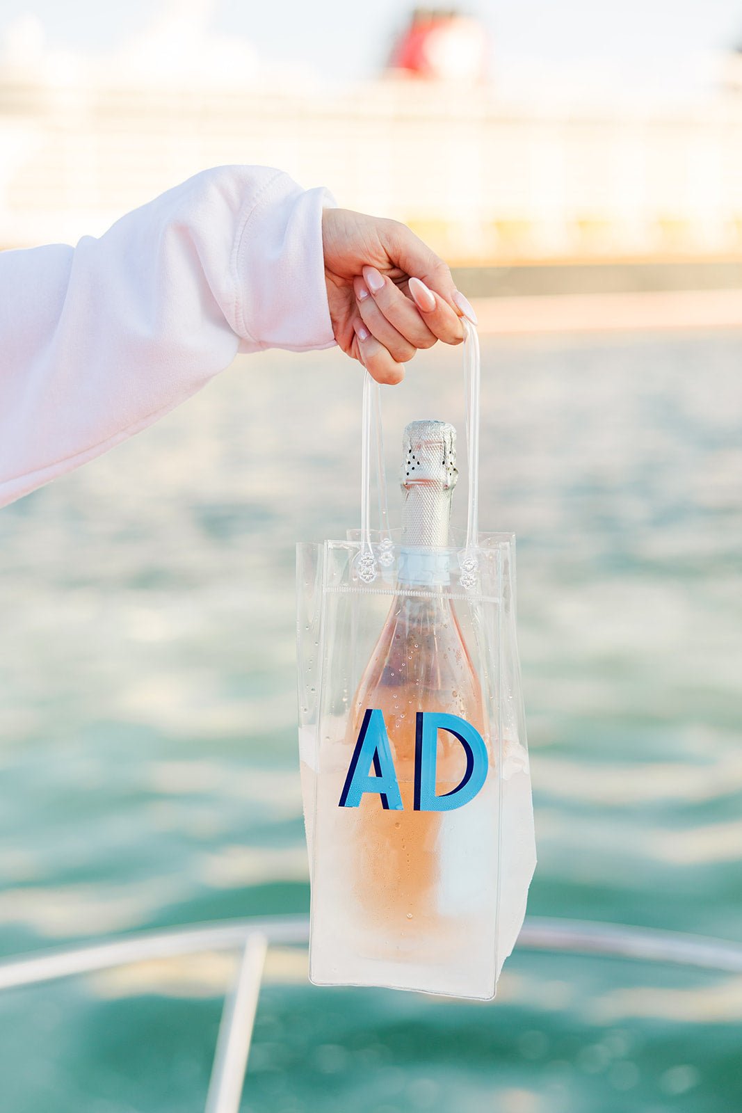 A clear wine bag that is customized with a monogram in blue writing
