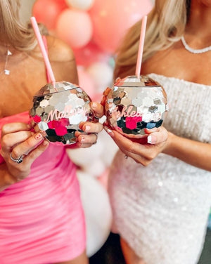 Two women hold out their personalized disco ball tumblers