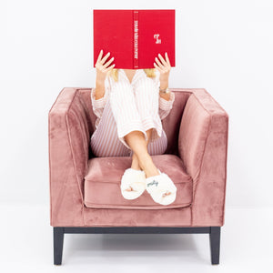 A girl sits in a chair reading a book in her customized slippers