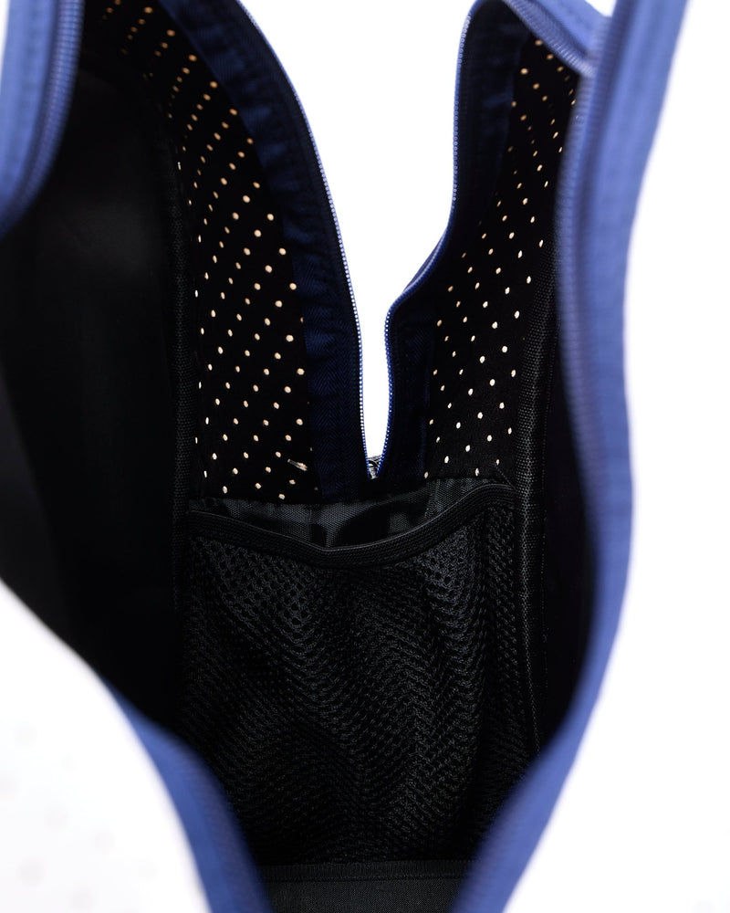 A navy and white pickleball bag is opened to show the interior pocket to hold a water bottle.