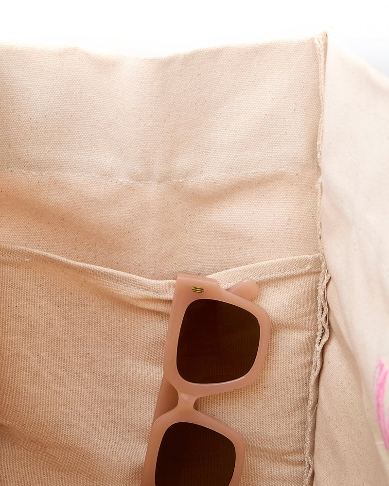 A pair of sunglasses hangs from the interior pocket of a weekender bag.