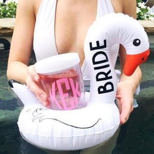 A woman puts her monogrammed tumbler into a swan drink float which has "Bride" written up the neck in black.