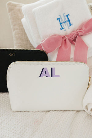 A white leather pouch is customized with a purple monogram.