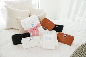 A group of leather pouches and bath towels are customized with monograms.