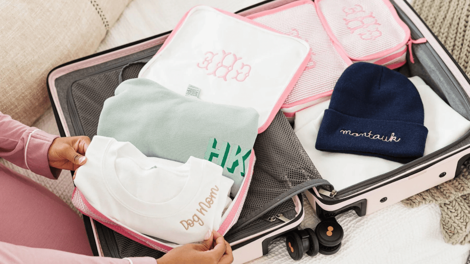Pink Lugagge Packed With Monogrammed Hats, Sweatshirts, and Packing Cubes
