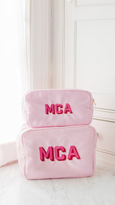 Pink pouches personalized, sitting on a bathroom counter