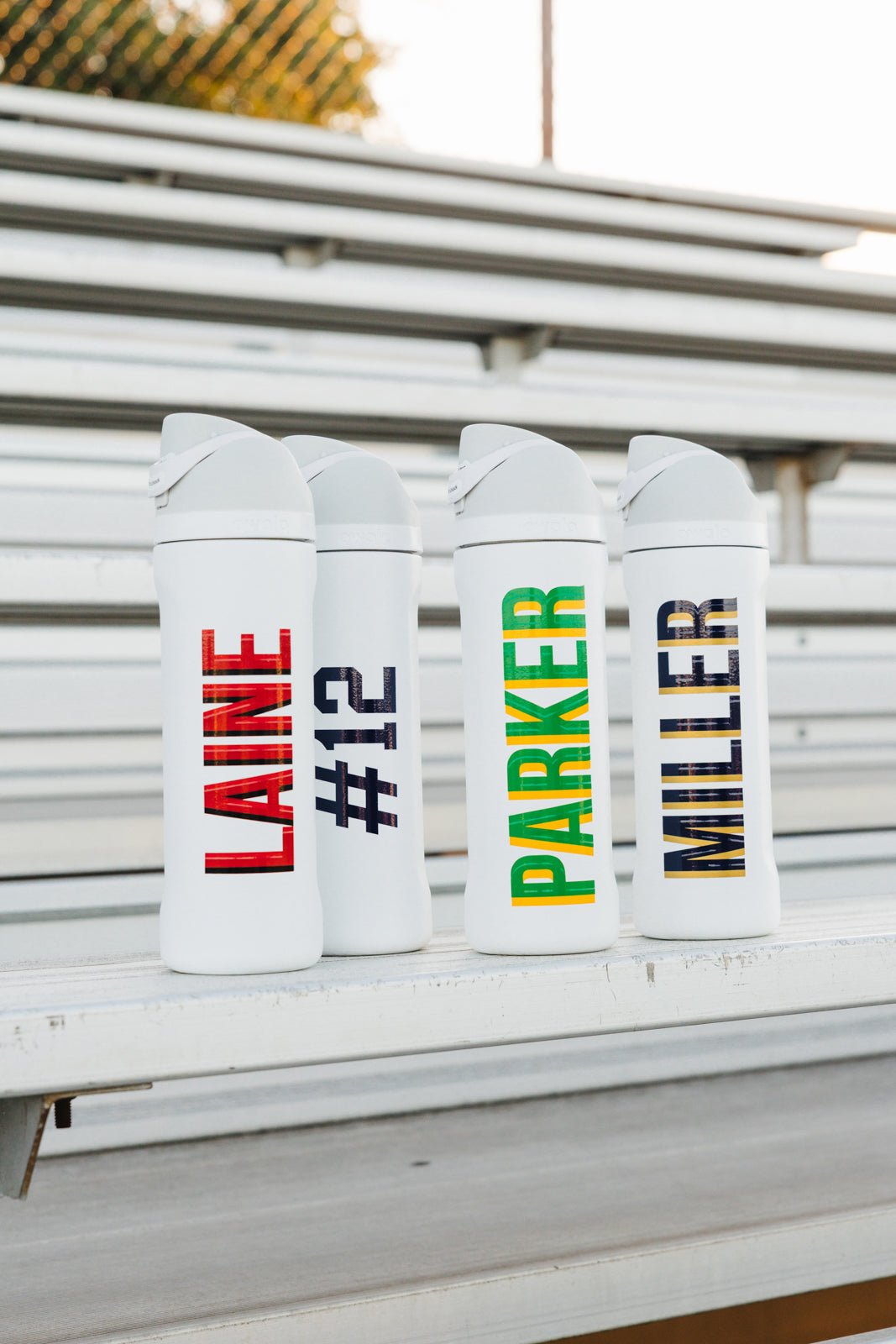 Two 24 oz white tumblers with flip lids, monogrammed with green “#12” and red “LAINE”
