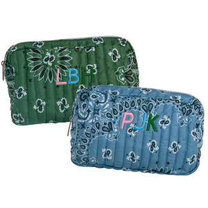 Two quilted zippered pouches with bandana prints, one green and one blue, each featuring colorful embroidered initials. The green pouch shows 'LBH' in pink, light blue, and dark green, while the blue pouch shows 'PJK' in pink, light blue, and dark green.