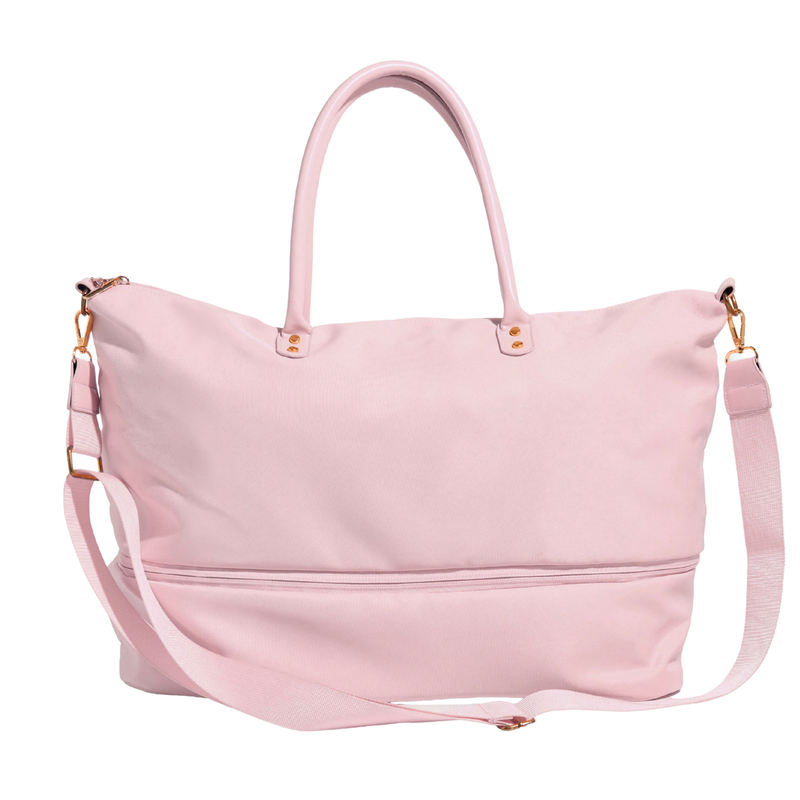 A light pink nylon duffel bag with dual top handles, a detachable shoulder strap, and gold-tone hardware, shown against a plain white background.