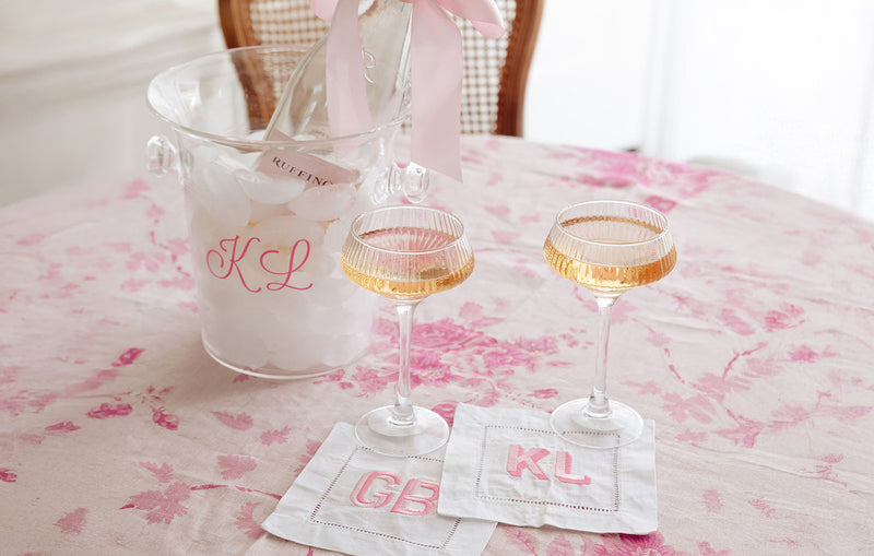 Champagne glasses, acrylic ice bucket personalized with KL initials, two cocktail napkins personalized with GB & KL initials