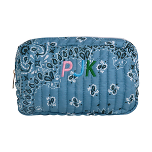A blue quilted cosmetic pouch with a paisley bandana pattern and colorful embroidered letters 'PJUK' on the front, shown on a plain white background.
