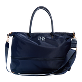 A navy blue nylon duffel bag with top handles, a detachable shoulder strap, and gold-tone hardware. The front features a zippered pocket and the initials 'CHS' in white embroidered lettering, set against a plain white background.