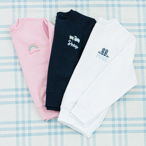 Three personalized children's sweaters featuring unique embroidered designs