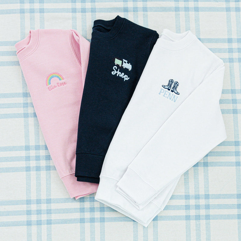 Three personalized children's sweaters featuring unique embroidered designs