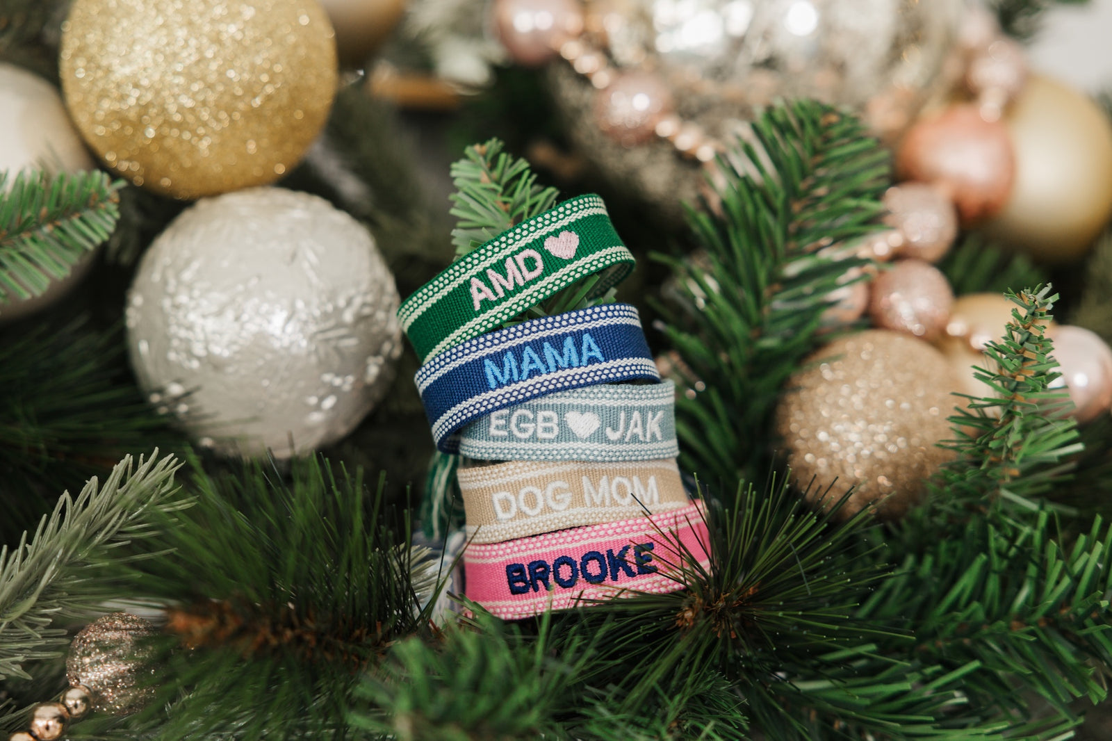 A pink bracelet and a blue bracelet are customized with embroidered names.