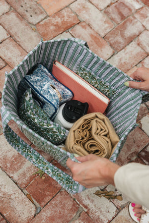 Green Block Print Tote filled with travel essentials, including a pouch, a book, a tumbler, and a scarf.