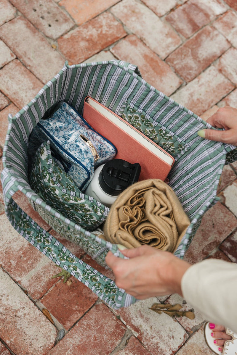 Green Block Print Tote filled with travel essentials, including a pouch, a book, a tumbler, and a scarf.