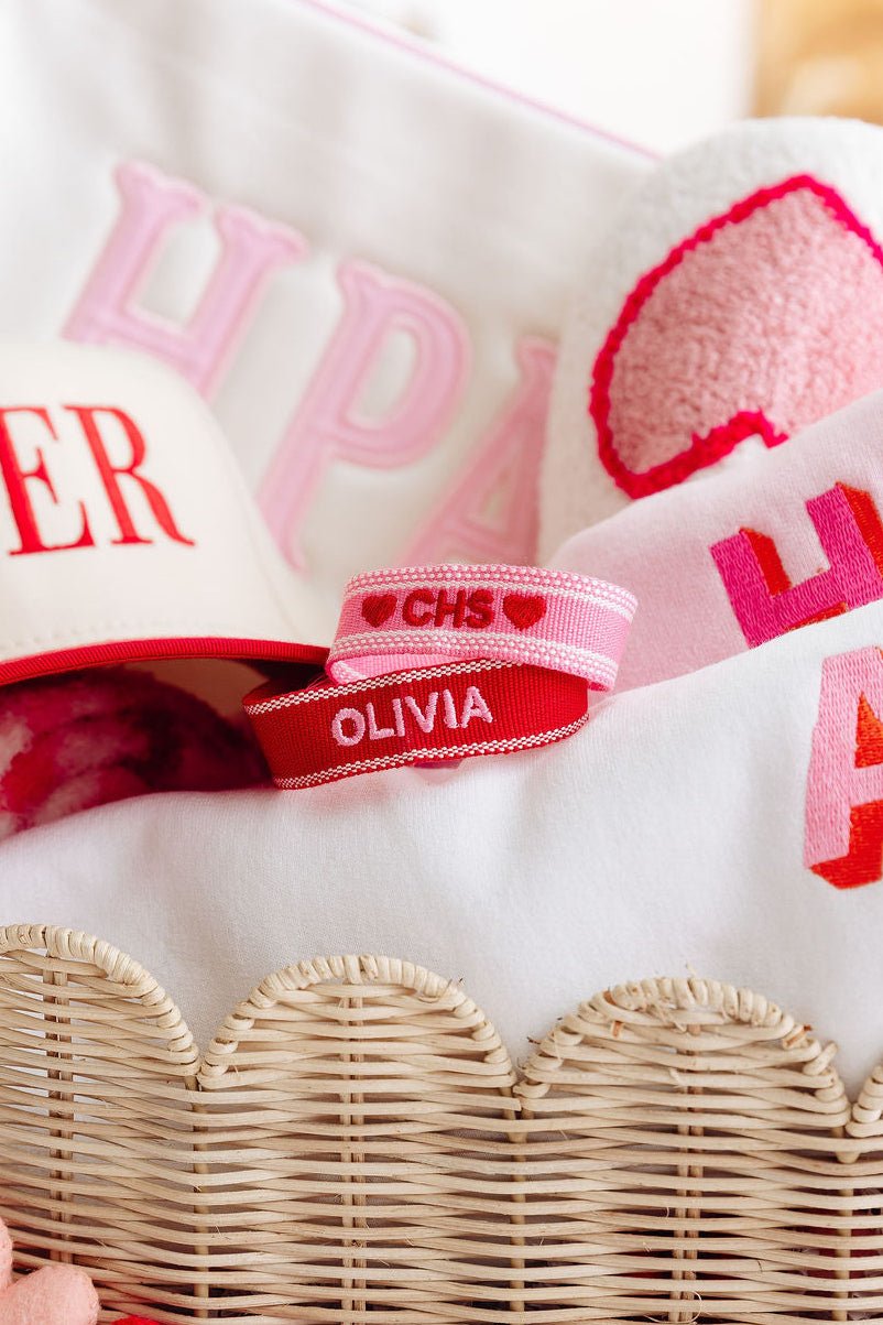 A pink bracelet and a blue bracelet are customized with embroidered names.