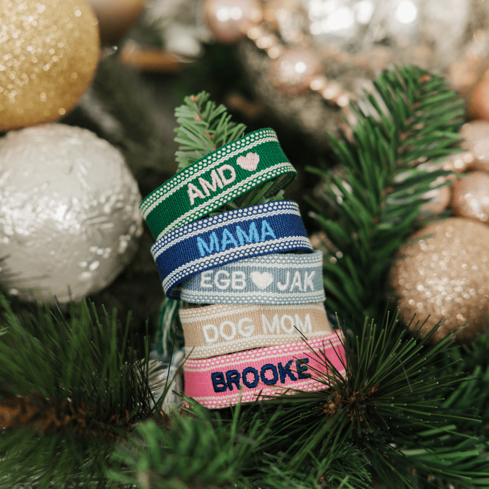 A pink bracelet and a blue bracelet are customized with embroidered names.