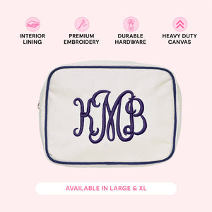 Cream canvas pouch with navy trim monogrammed 'KMB' in navy script, with icons describing interior lining, premium embroidery, durable hardware, and heavy duty canvas.