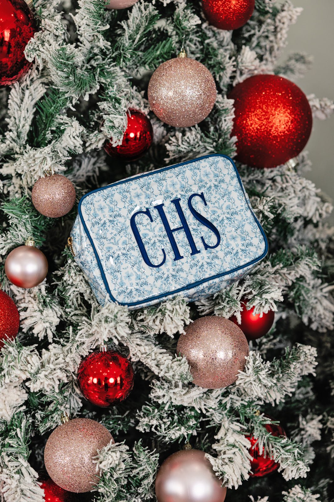 Two embroidered blue floral clear-coated pouches in large and small sizes with “JBH” monogram in bold navy letters.