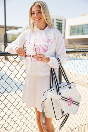 A girl wears a custom white sweatshirt with a pink pickleball design printed on it 