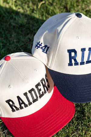 Cream vintage trucker hats: red-brim “RAIDERS” and navy-brim “#41 RILEY,” highlighting the Custom Collegiate Vintage Trucker Hat.
