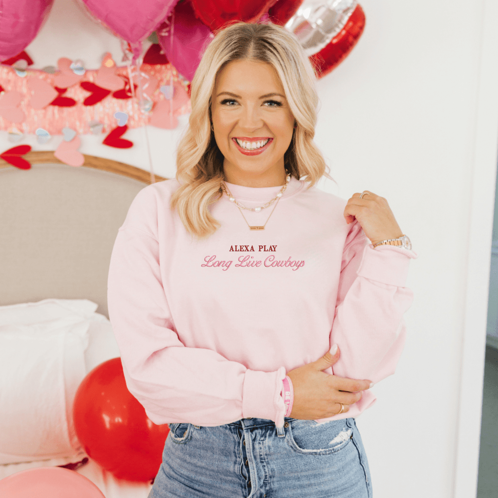 Custom Embroidered Phrase Sweatshirts featuring playful text designs—one in blush pink reading 'Pinot Noir Is For Lovers' and one in classic white embroidered with 'Alexa Play Long Live Cowboys' in red and pink fonts. Cozy and stylish, perfect for expressing your personality.