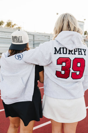 Friends in hoodies at track wearing cream trucker hats with sport puff—Custom Sport 3D Puff Vintage Trucker Hat.