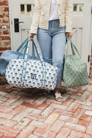 Woman carrying green Embroidered Block Print Duffel bag with floral design and embroidered monogram, perfect for weekend trips.
