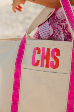 A pink canvas tote is customized with a pink and orange embroidered monogram.