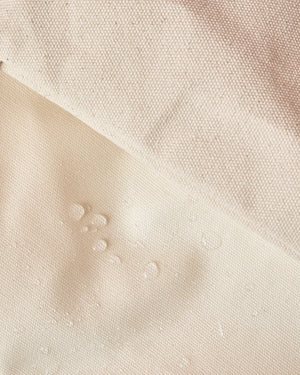 Some droplets of water accumulate on the outside of the wipeable surface on the canvas tote